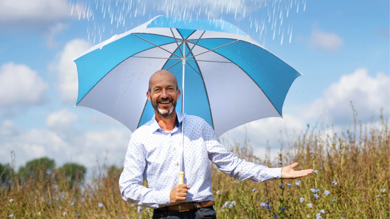 Reinier van den Berg met een paraplu in een zomers veld
